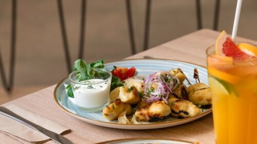 Grillezett sajtos tányér tzatziki mártással és salátával, mellette narancslé.